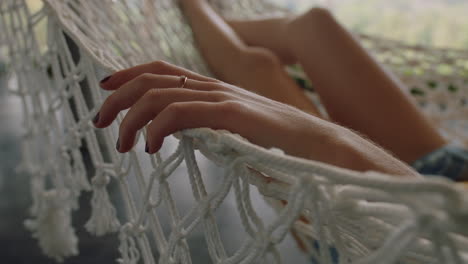 close up hand of woman in hammock gently moving fingers sleeping comfortable on holiday in vacation resort swaying peacefully on lazy summer day