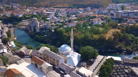 circling drone shot of a mosque in mostar with famous bridge in the background