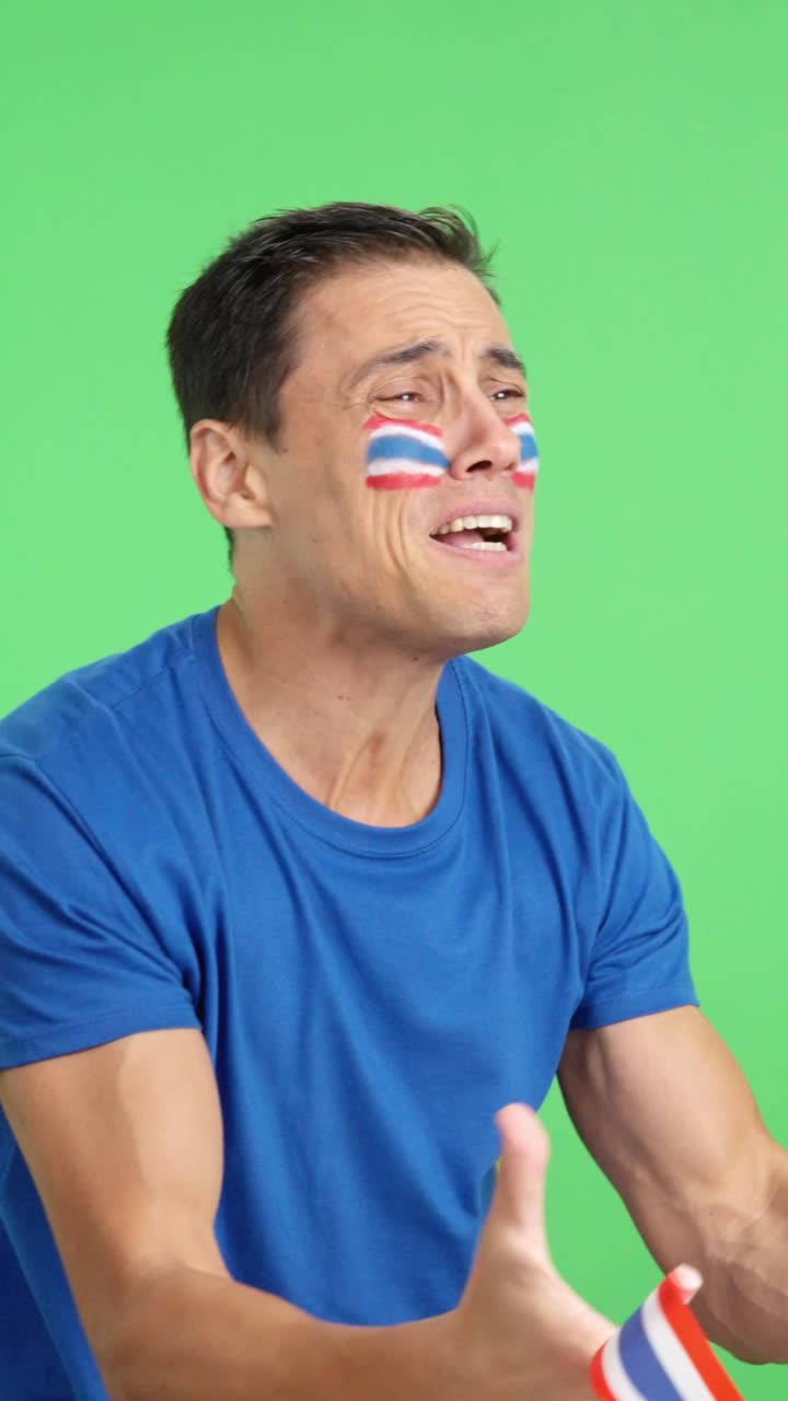 Nervous man cheering for Thailand during a match looking away