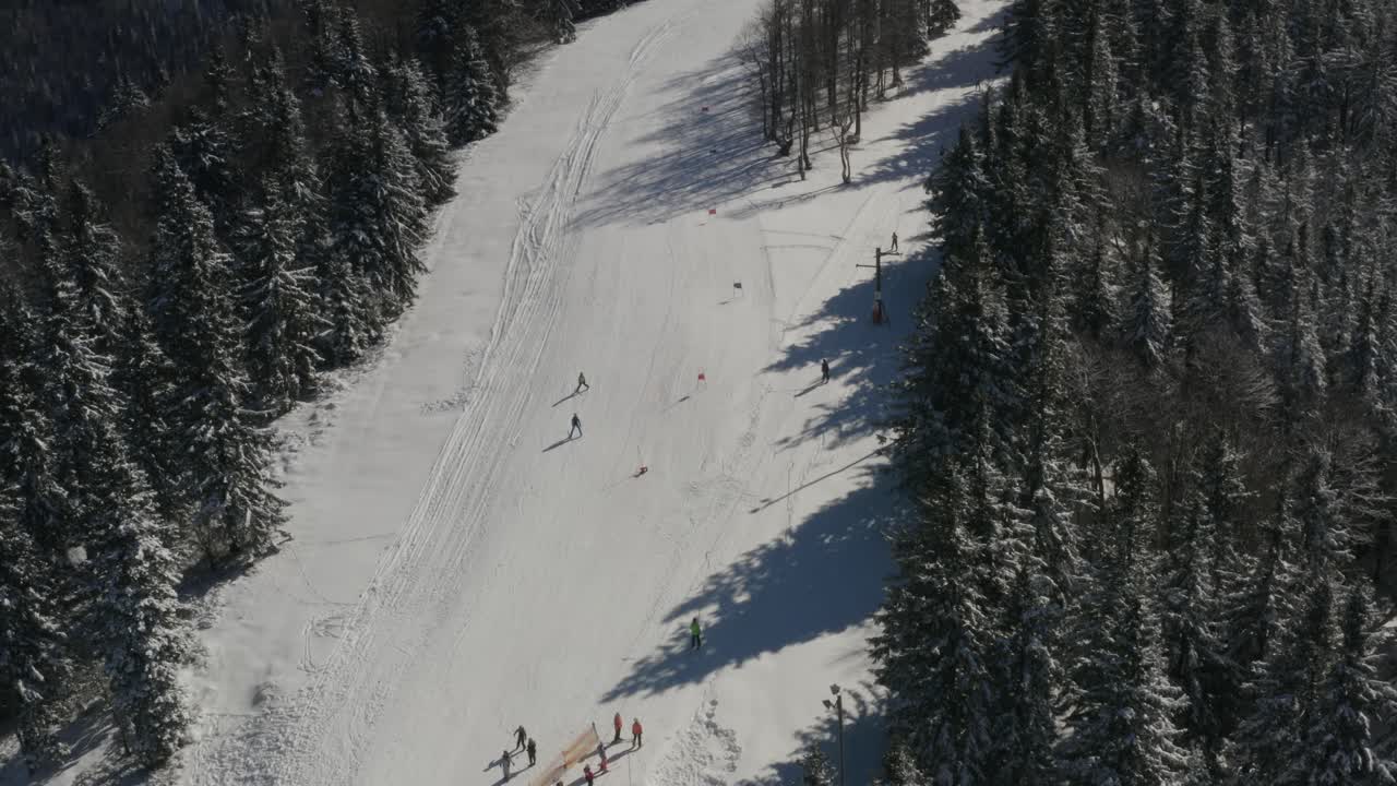 Skiers go down a track in Kope Slovenia at the Pohorje mountains, Aerial pan right shot