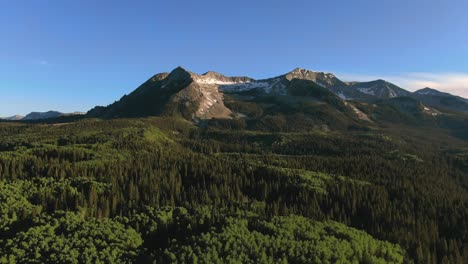 lush green mountain hills covered in pine trees with east beckwith mountain peak in background