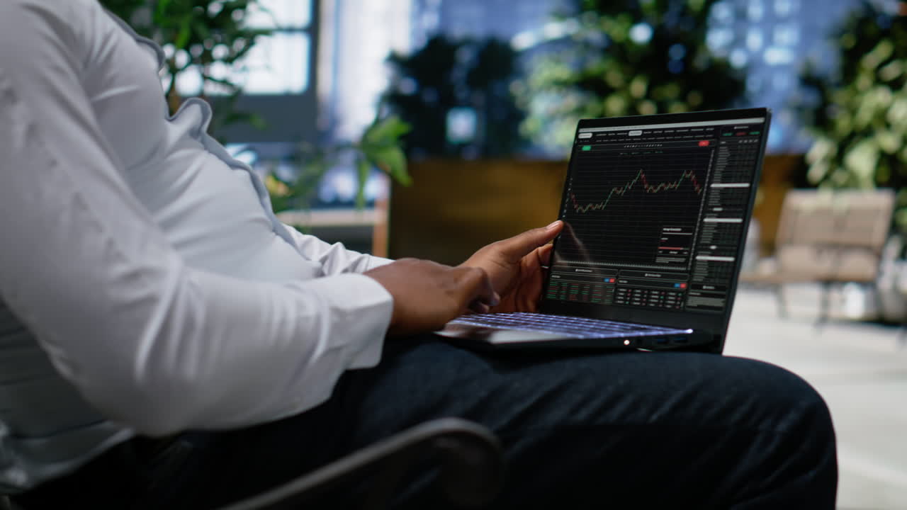Black man navigating stock trading indicators online on laptop