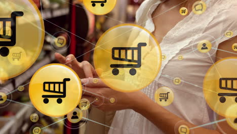 red de iconos digitales contra la sección media de la mujer que usa un teléfono inteligente en la tienda de comestibles