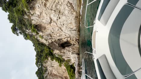 Boat-parked-up-beside-The-Blue-Cave-with-beautiful-rocky-cliffs-ahead-at-The-Kolocep-Island,-Croatia