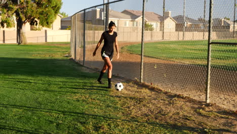 A-female-soccer-player-running-with-a-football-dribbling-up-the-grass-field-during-a-team-sport-practice
