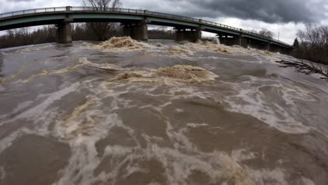 flooded river under bridge in stormy weather