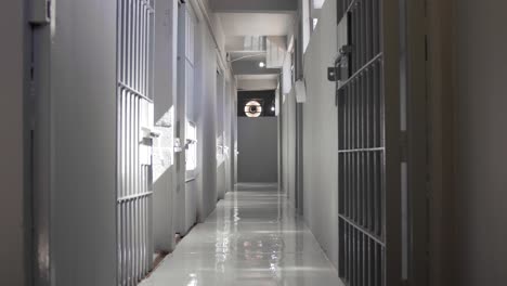 gray hallway full of empty prison jail cells during the day