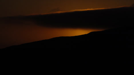 lapso de tiempo del sol desapareciendo detrás de la cima de la montaña al atardecer