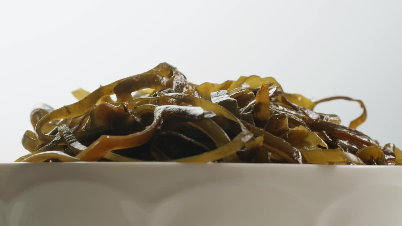 Japanese wakame sea weed laminaria chuka fermented food. Close-up on a detail of Hiyashi Wakame Chuka or seaweed salad or seaweed with sesame seeds on a plate. Top view. Seafood background.