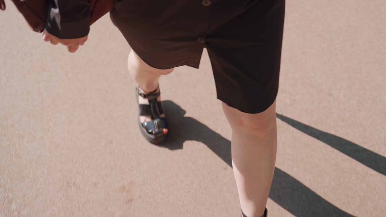 밝은 햇살 아래 우산을 쓰고 걷는 모습, 그림자가 드리워진 낮 시간의 보행 장면, 햇볕이 좋은 야외에서 한가롭게 산책하는 사람의 클로즈업 이미지