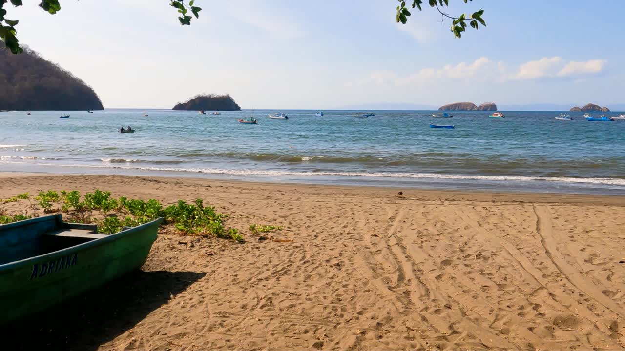 bote de madera en una playa tropical con un árbol en un día soleado, playa coco en guanacaste, costa rica