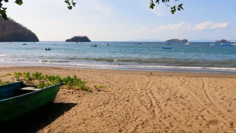 Wooden-boat-on-tropical-beach-with-a-tree-on-a-sunny-day,-Coco-Beach-in-Guanacaste,-Costa-Rica