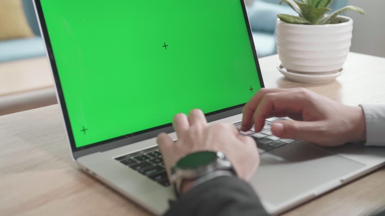 un hombre de negocios asiático con traje de negocios escribiendo en una computadora de pantalla verde mientras trabaja en casa.