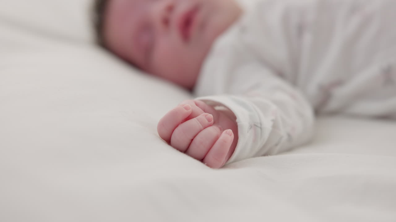 Hand, newborn and sleeping on bed in nursery