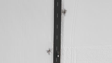 aerial shot of cars driving on a road, fresh snow covered winter landscape scene