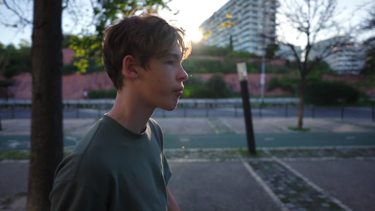 Teenager in green shirt walking outdoors in Lisbon with apartment buildings in background