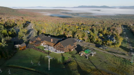 aerial view of saddleback maine base lodge with fog and mountains in the background during autumn