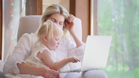 mother and toddler daughter using laptop at home