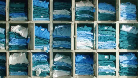 neatly organized stack of folded clothes in various shades of blue and green organized in shelves, showcasing a calm and tidy environment