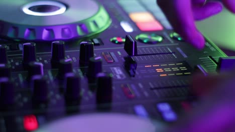 a teenage edm techno dj spins a record and adjusts the volume knobs