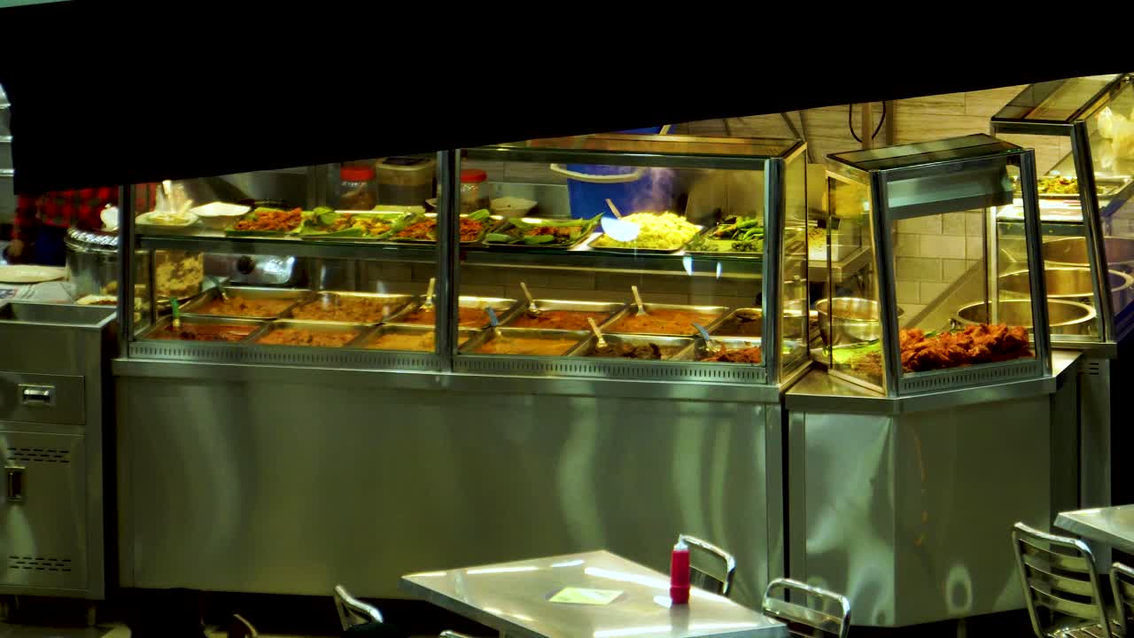 밤에 냄비 금속 더미에서 증기가 뿜어져 나오는 아시아 중국의 작은 뷔페 카페는 솔직하고 한적한 음식 용기