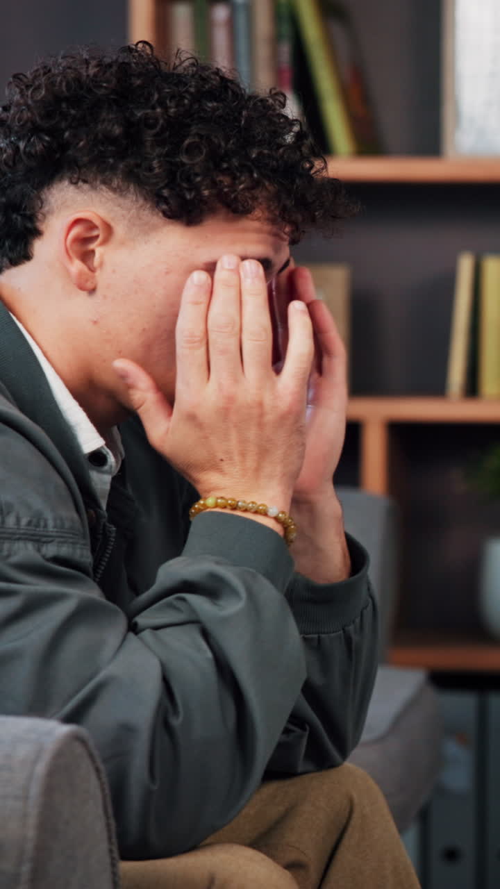 Uomo che si copre il viso con le mani, con espressione stressata e ansiosa