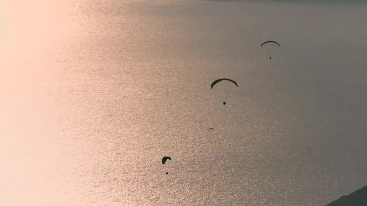 Parapendisti che planano sull'oceano al tramonto
