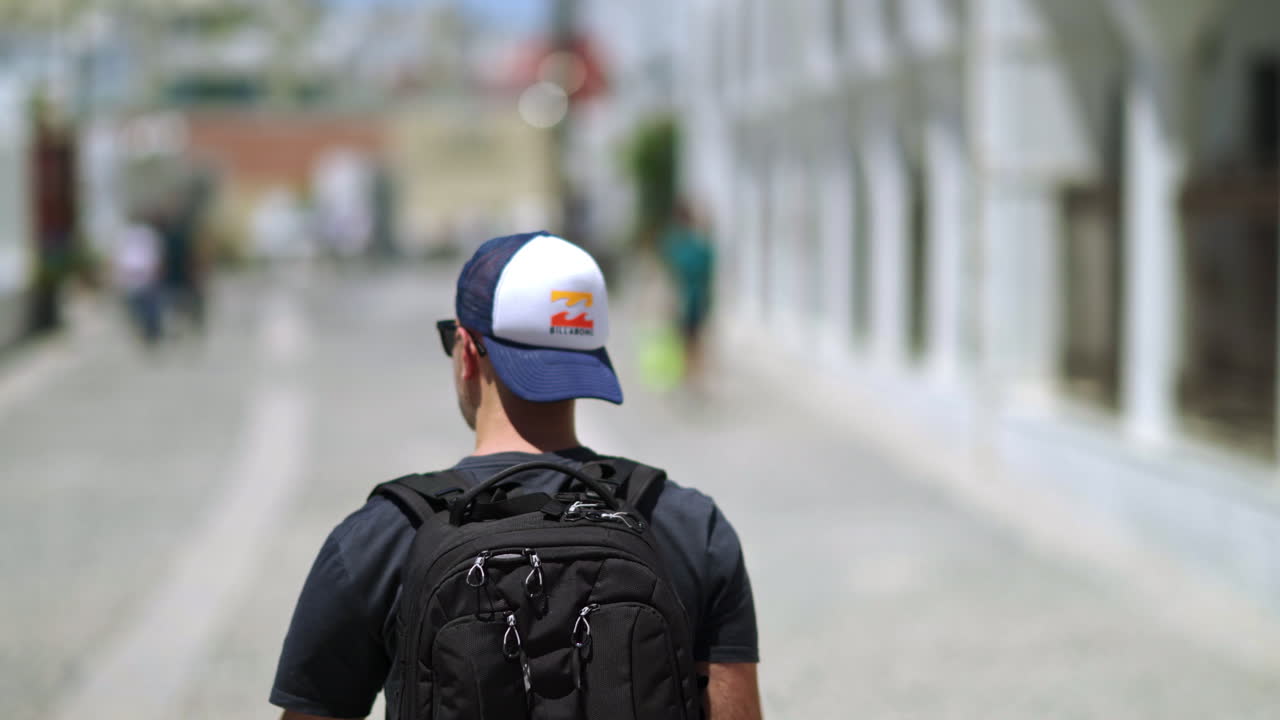 Seguendo un uomo con uno zaino, che cammina su una strada pubblica.