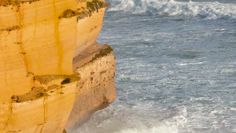 dynamic waves crash against the iconic limestone cliffs of the twelve apostles, captured in natural daylight along the great ocean road