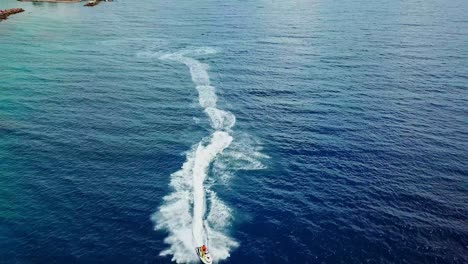 dolly out aerial view of a person on a jet ski on the shores of mambo beach in curacao, dutch caribbean island