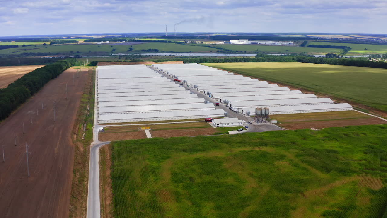Innovative farm on field in the countryside. Large agricultural area on beautiful green landscape. Harmful factory among nature. Aerial view.