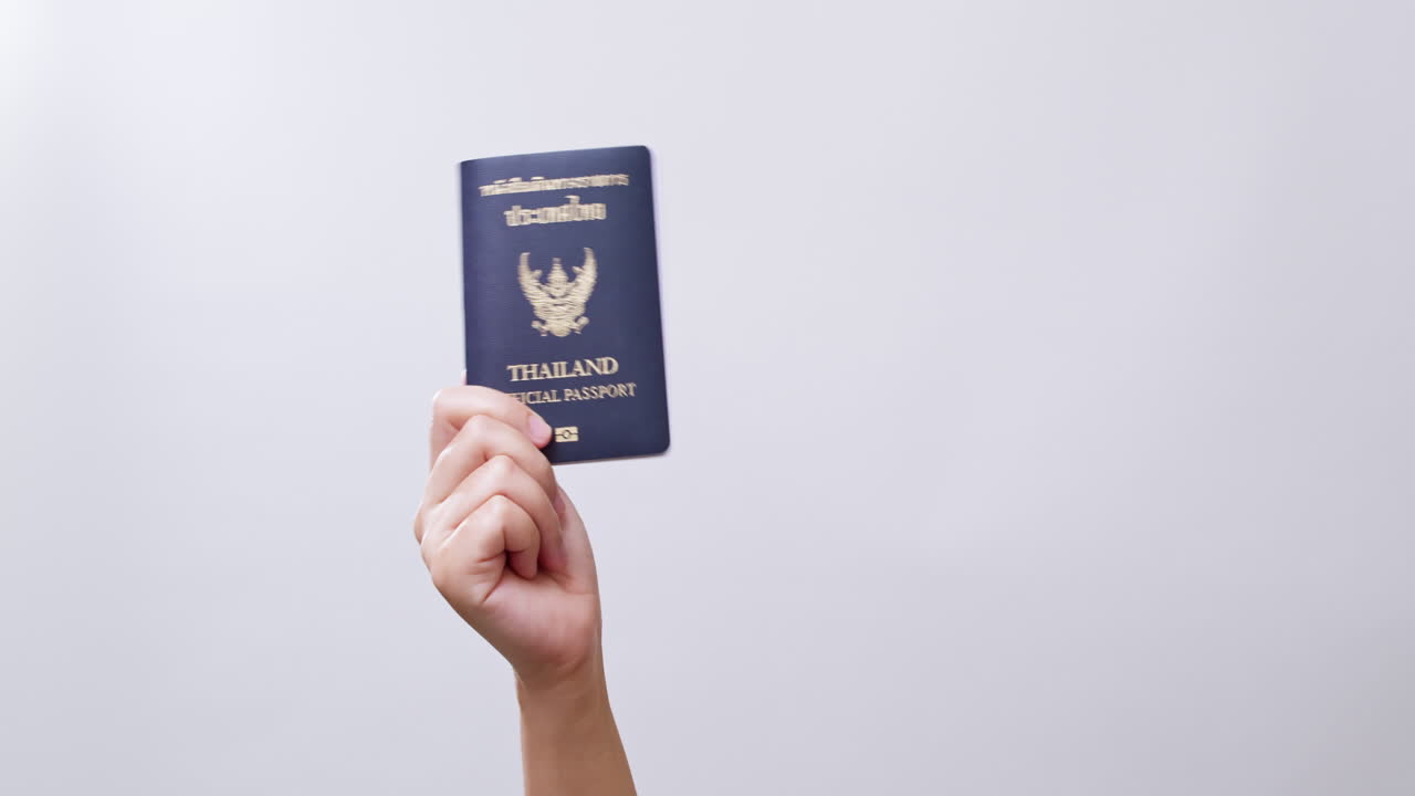 Woman's hand shows the Thailand Passport ready for travel in white studio background with copy space.