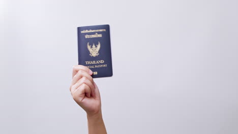 woman's hand shows the thailand passport ready for travel in white studio background with copy space.