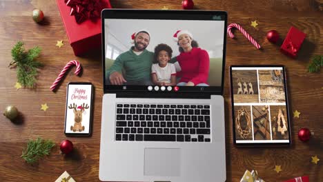 Family-wearing-snatas-hats-on-video-call-on-laptop,-with-smartphone,-tablet-and-decorations