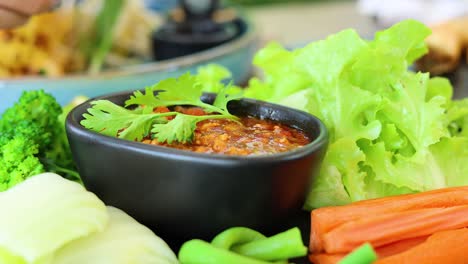 dipping vegetables into a spicy chili sauce