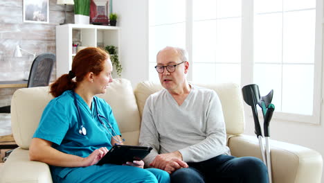 Enfermera-Caucásica-Tomando-Notas-Sobre-La-Salud-De-Los-Ancianos-En-Una-Luminosa-Y-Acogedora-Residencia-De-Ancianos