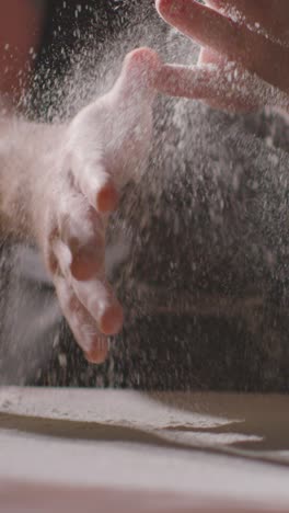 Vertical-Video-Low-Key-Shot-Of-Person-In-Apron-Rubbing-Hands-With-Flour-Before-Baking