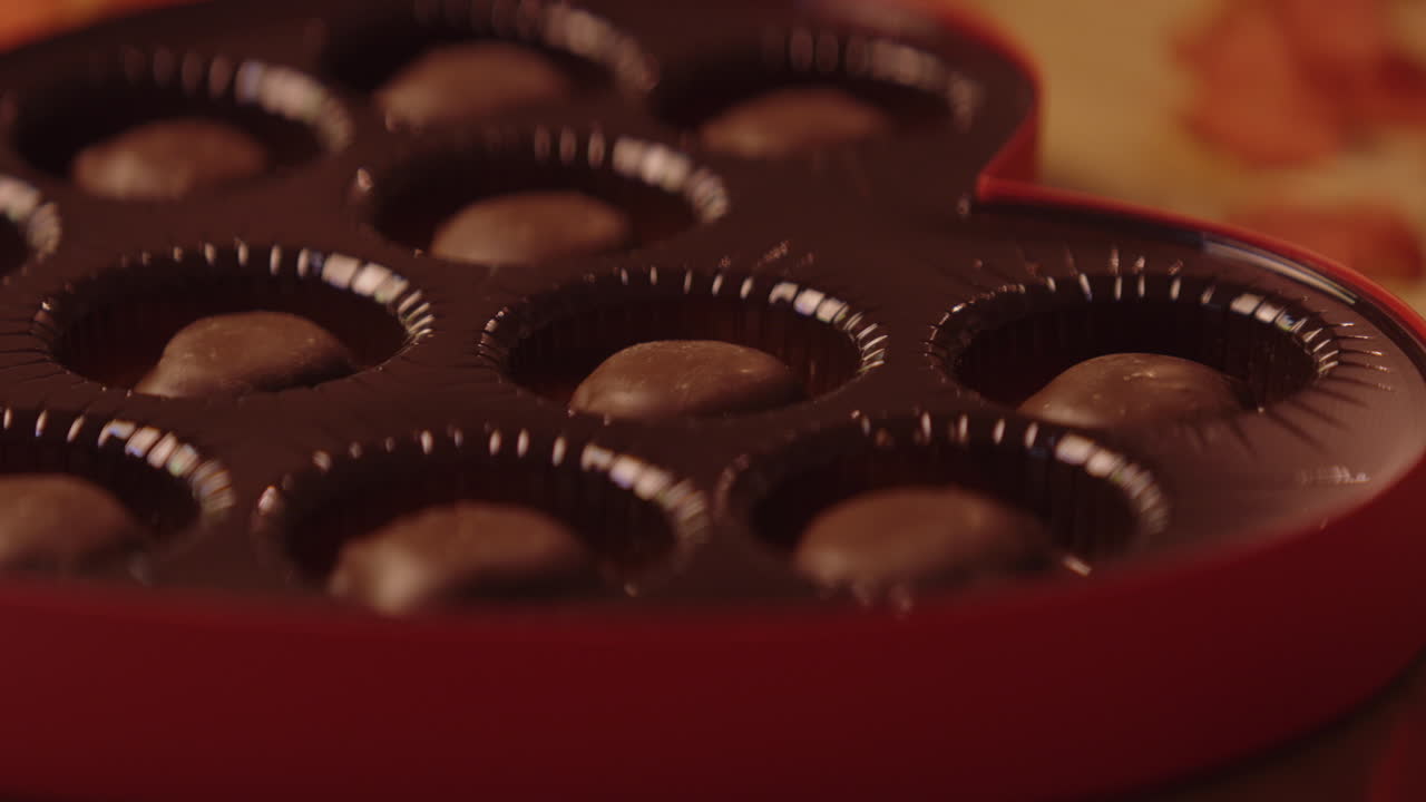 Hand placing chocolate candies in a heart-shaped box