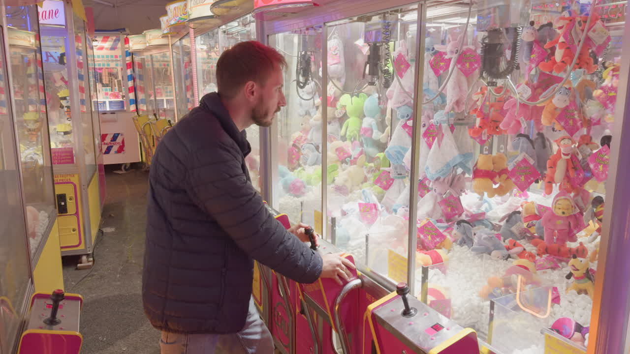 Man playing claw machine at a small local fair in Montrichard Val de Cher France at night