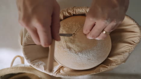 hands scoring sourdough bread dough