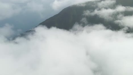 volando sobre las nubes sobre una montaña verde