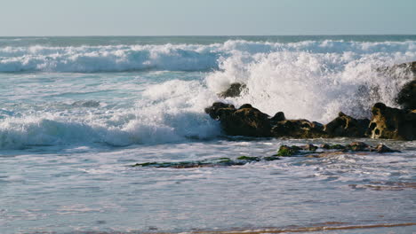 Olas-Blancas-Rompiendo-Rocas-En-La-Mañana-Soleada.-Vista-Del-Paisaje-Del-Océano-Asaltante.