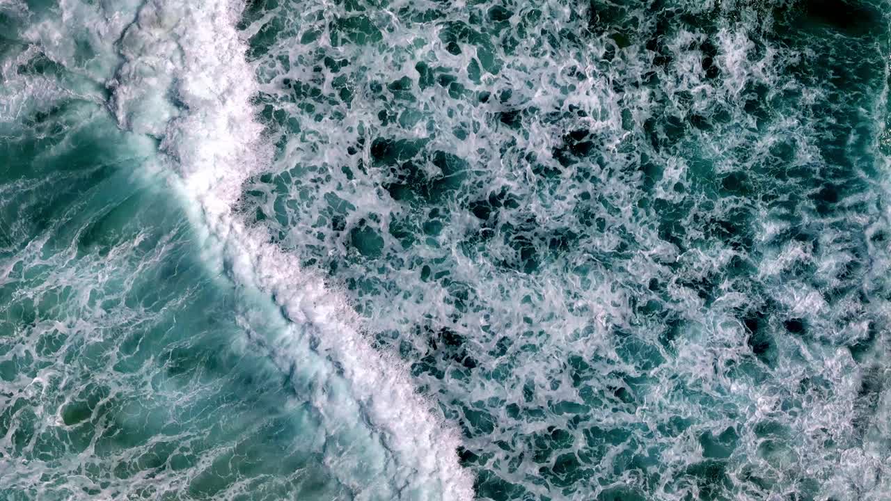 a beach with a wave coming in to the shore and a sandy beach with a green ocean and a sandy shore