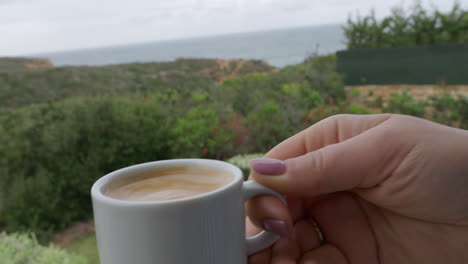 woman having a cup of coffee on the balcony with nature view