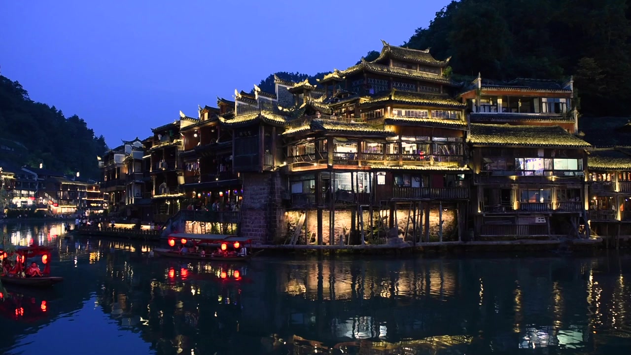Vista noturna da Cidade Antiga de Fenghuang na Província de Hunan, China, destacando seu encanto histórico com arquitetura chinesa tradicional, casas sobre palafitas, ruas de paralelepípedos e paisagens ribeirinhas.
