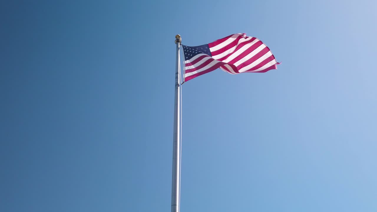 bandera americana ondeando orgullosamente con fondo de cielo azul claro, cámara lenta