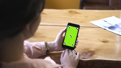 woman holding a phone with a green screen