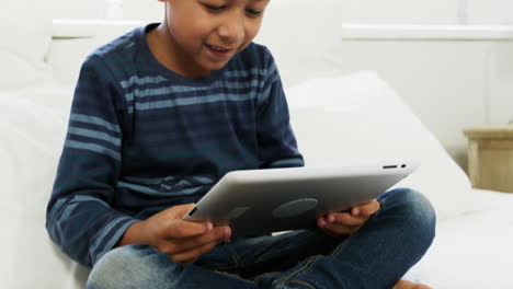 niño usando una tableta digital mientras se relaja en la cama