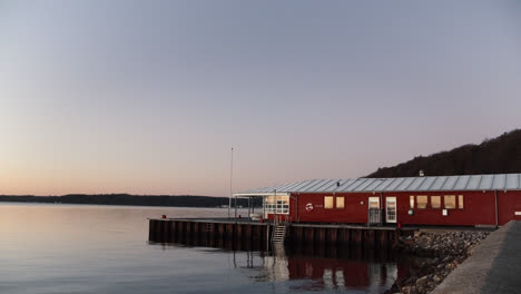 peaceful sunrise at the waterside in denmark red house