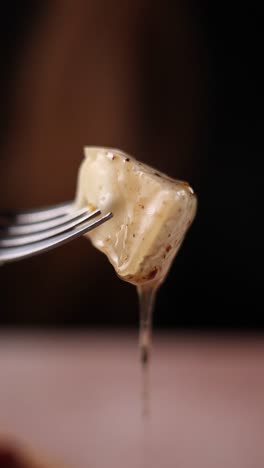 a piece of cheese on a fork with dripping sauce